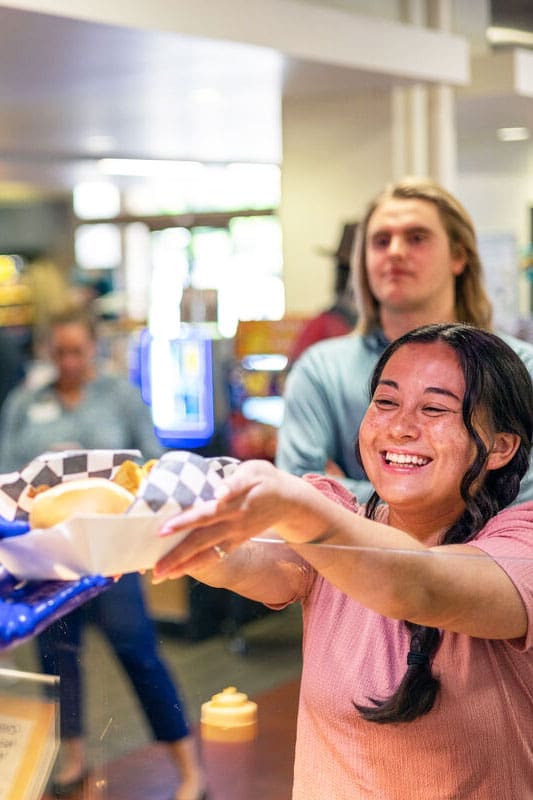 Cook smiling behind pizza station line